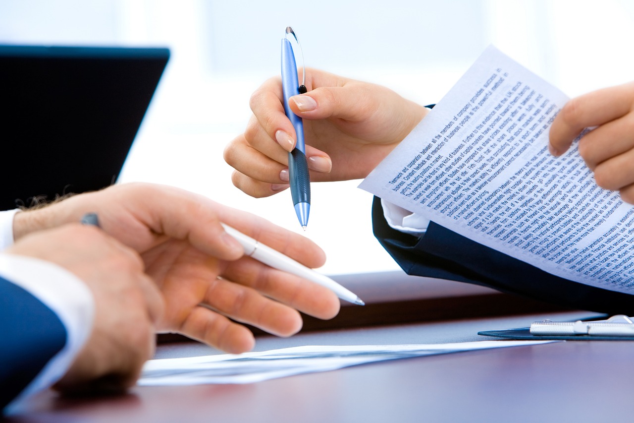 Declaração de imposto com documentos financeiros, assinatura e notebook sobre a mesa.