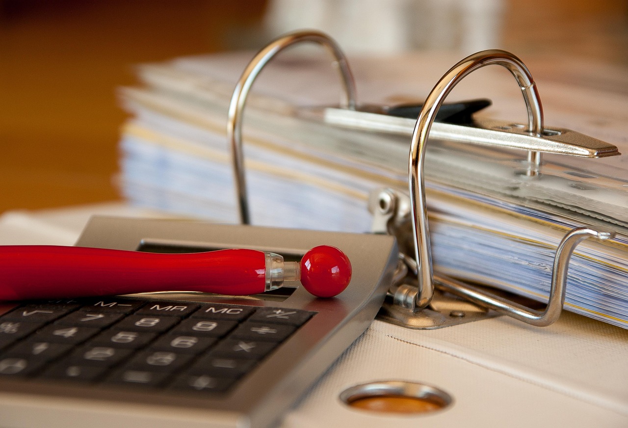 Analisando bitributação com calculadora e documentos de uma empresa sobre a mesa.