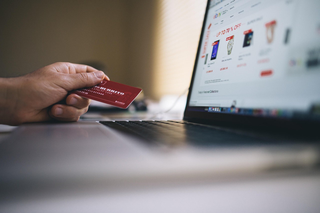 Plataformas digitais em operação de e-commerce e marketplace com cartão na mão e um notebook com site da compra.