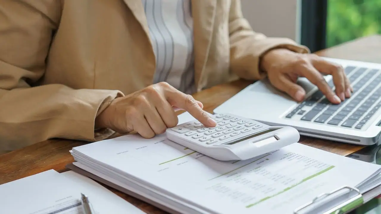 Pessoa usando calculadora e planilhas para montar o orçamento familiar no laptop