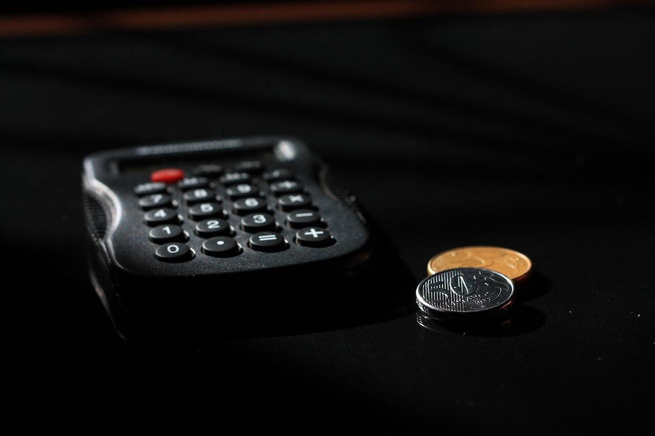 Calculadora com moedas representando gestão patrimonial.